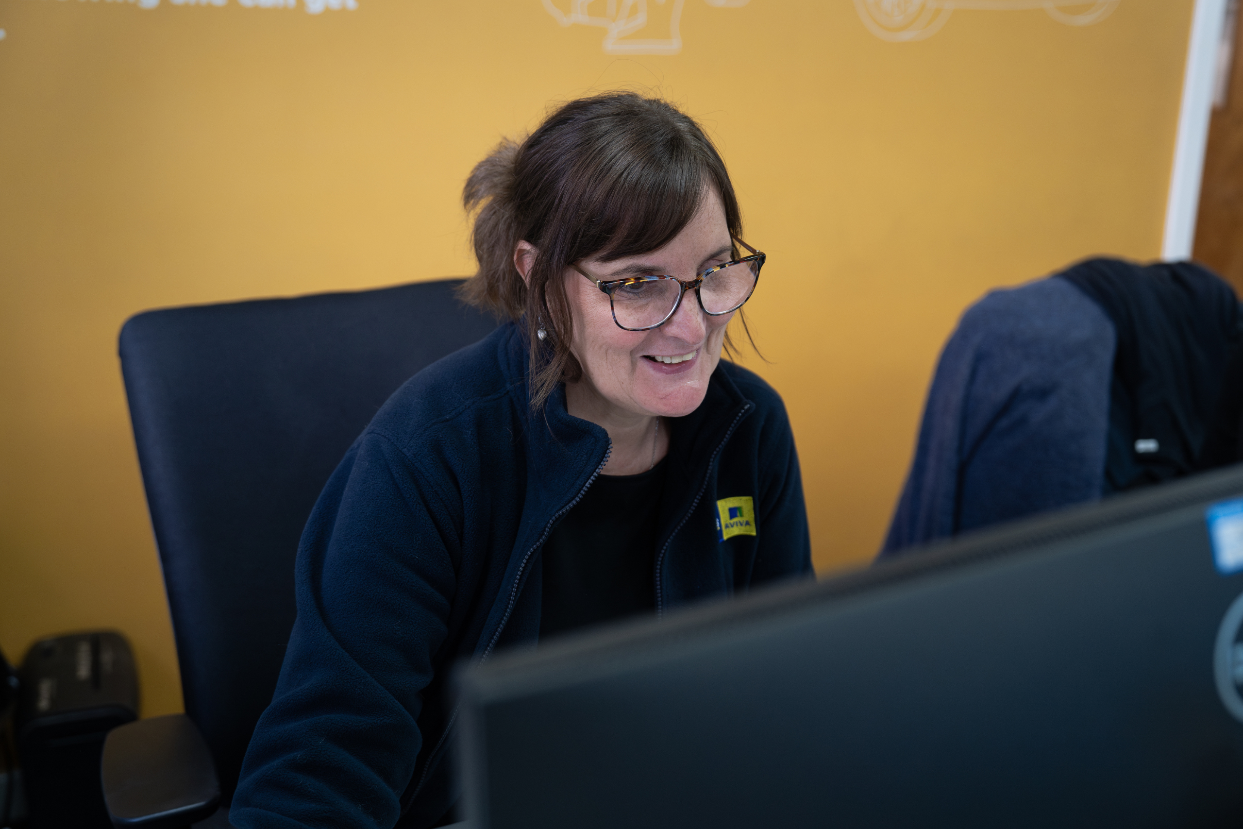 Image shows female customer service lead working at a desk.